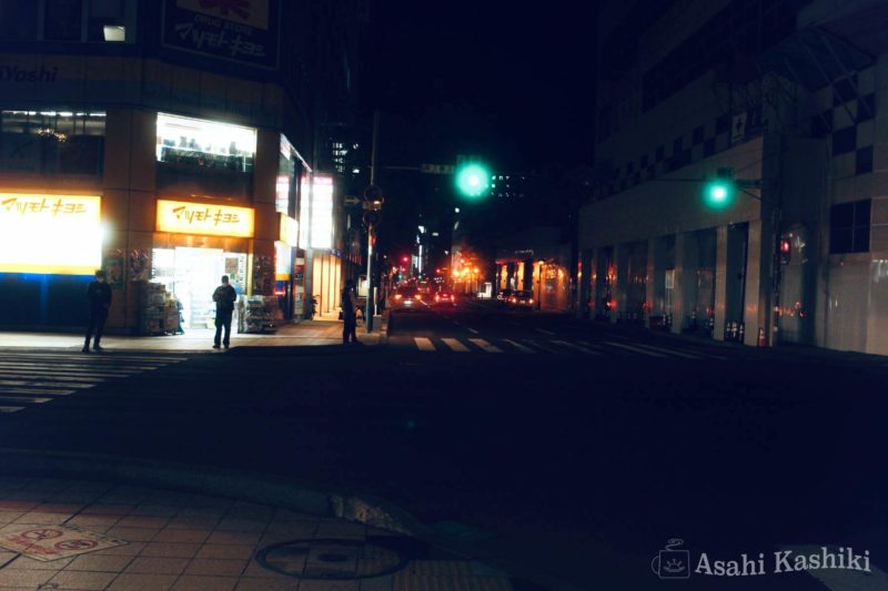 夜の街角に明るく立つ店々