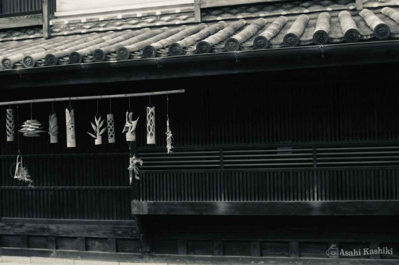 町並み保存地区の家屋を正面から撮ったもの。軒先には、竹で作られた、様々な形の飾りが10個近くぶら下げられている。