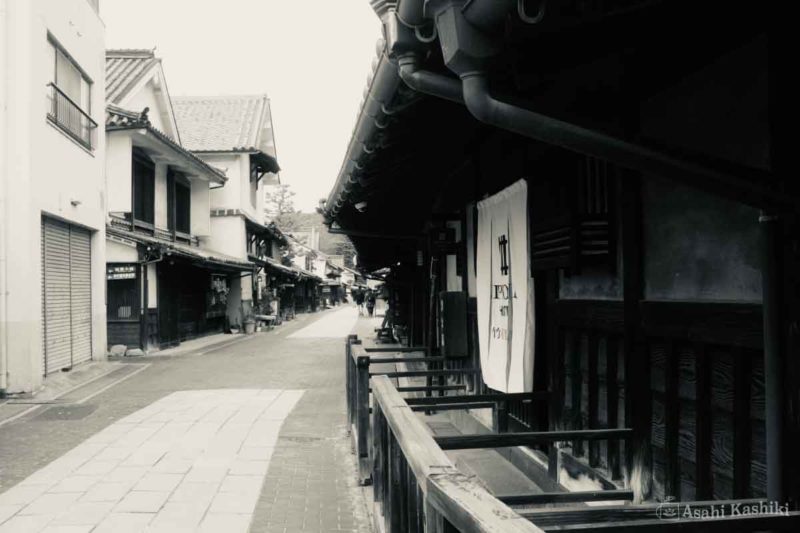 竹原町並み保存地区の通りの風景。重厚な瓦屋根の軒が連なり、手前にはホテルの暖簾がかけられている。